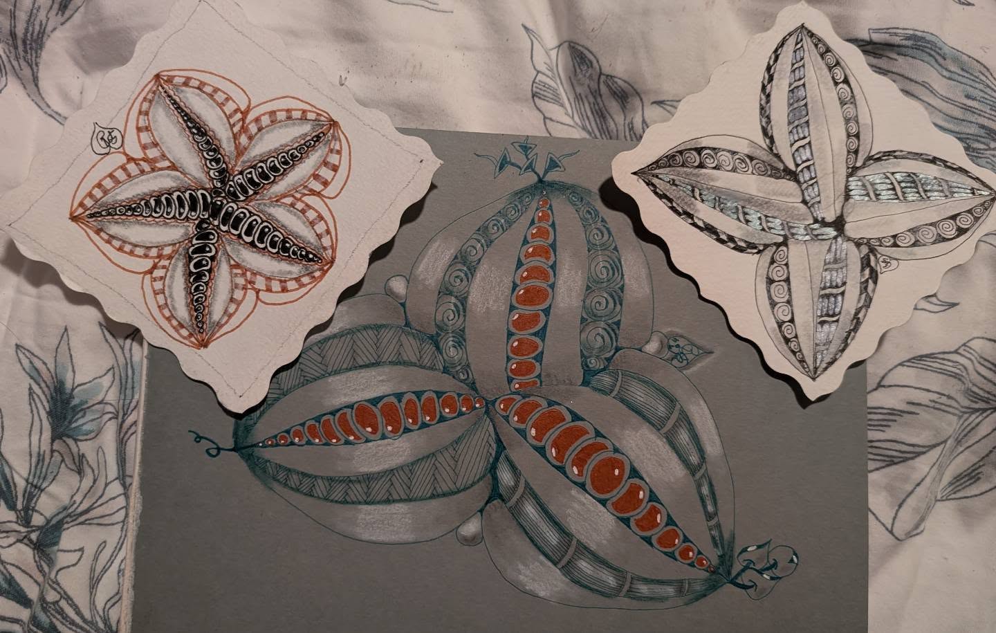 Three hand-drawn Zentangle triangle tiles in brown, black and white patterns